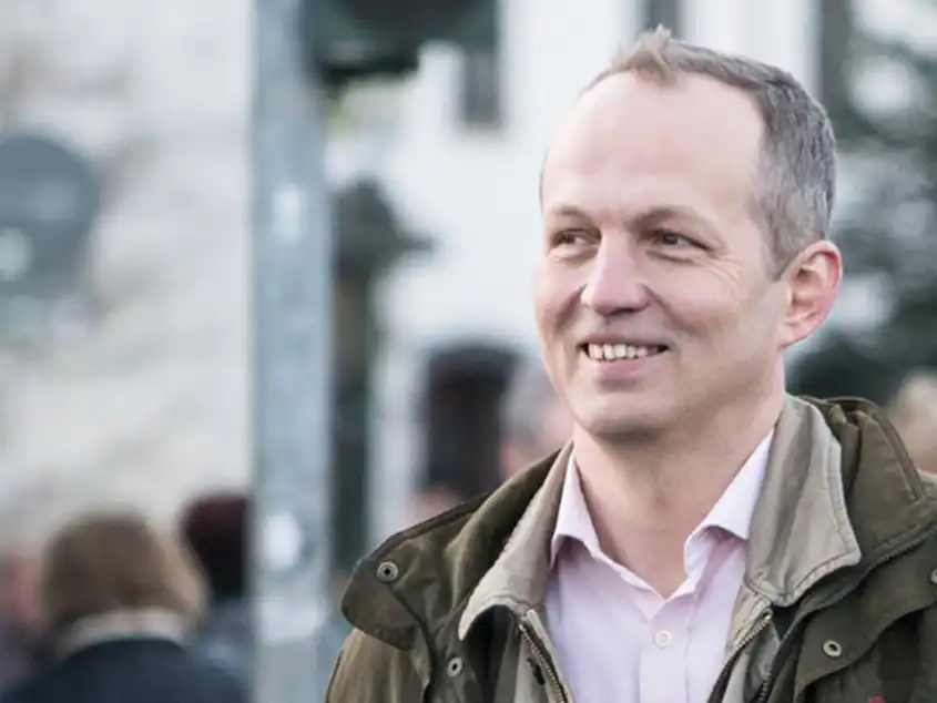 Mann lächelt und guckt Richtung Kamera