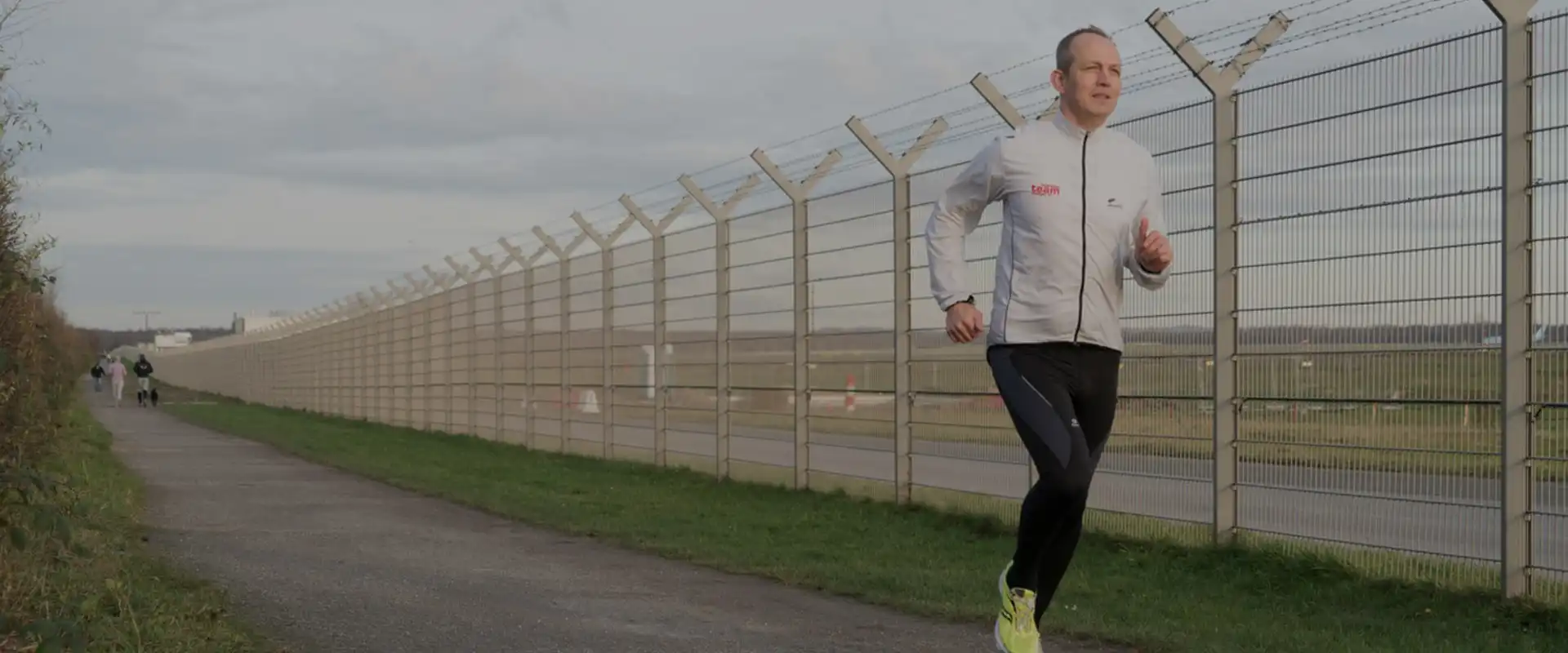 Ein Mann joggt neben einer Flugzeuglandebahn